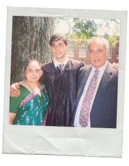 a college student in graduation robes with his parents