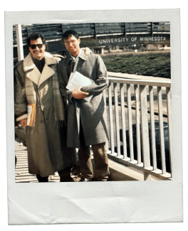 a student and faculty member stand together in front of a building that reads "University of Minnesota"
