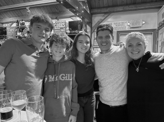 A black and white image of a family of five: two boys, a girl, a husband, and a wife