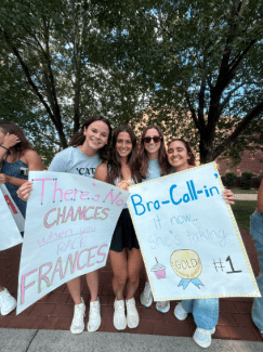 Four young women hold handmade posters that read "There's No CHANCES when you RACE FRANCES" and "Bra-Call-in it now... she's taking GOLD #1."
