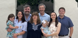Eight smiling individuals, including two babies
