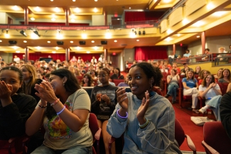 Students in the auditorium, clapping and smiling