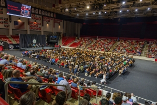 A colorful crowd seated in chairs on the court in Baker Sports arena, and in both sides of the stadium