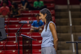 A side view of a female student in a blue blouse speaking into a microphone