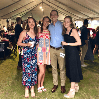 Four Davidson alums under a reunion tent outdoors, wearing festive spring clothing