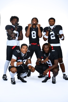 A group of football players on a white backdrop wearing striking black and red uniforms