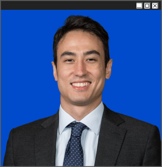 A man in a suit and tie with a smiling expression and short, dark hair in a blue browser window