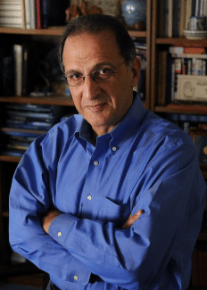a headshot of James Zogby with crossed arms smiling