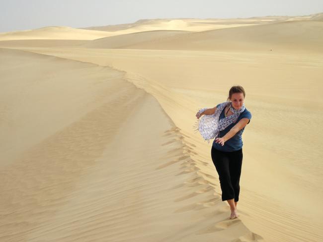 Girl walks along the edge of a sand dune in the Sahara
