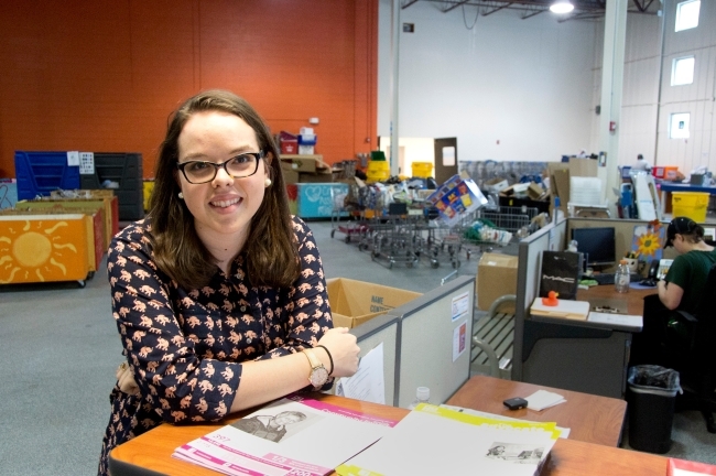 Student at internship leans over a counter with her workplace in the background
