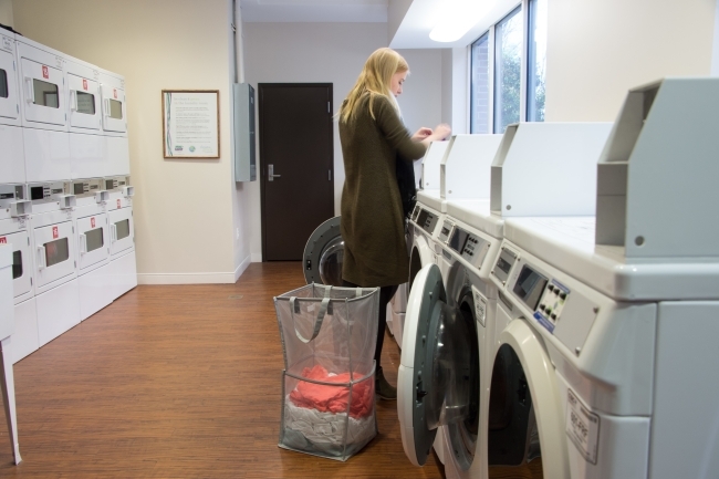 Laundry room in dorm with student doing her laundry with her hamper