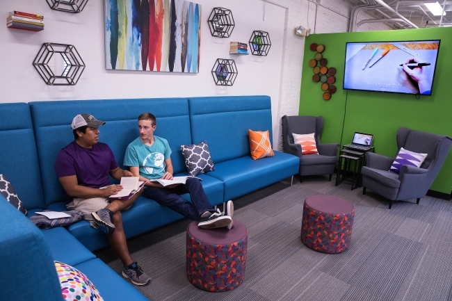 Two students talk while sitting on a couch