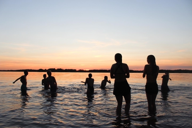 people playing in the waves at sunset