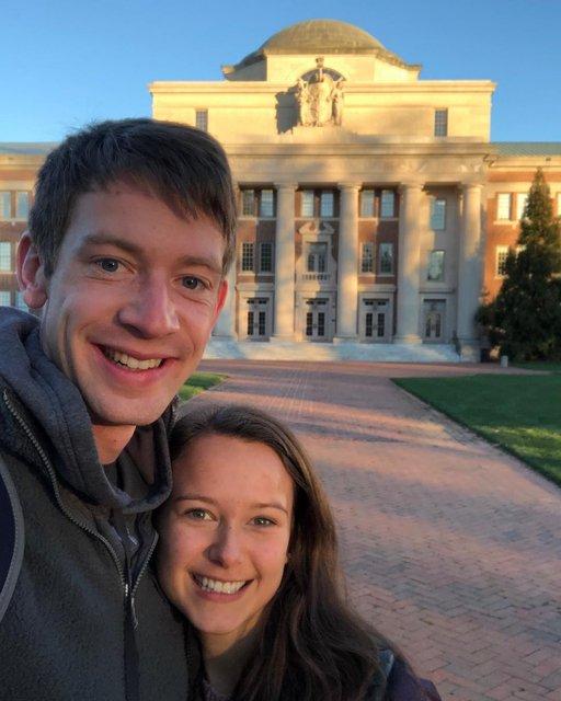 cute couple posing for picture on campus