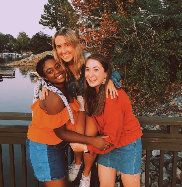 three friends holding each other on a bridge