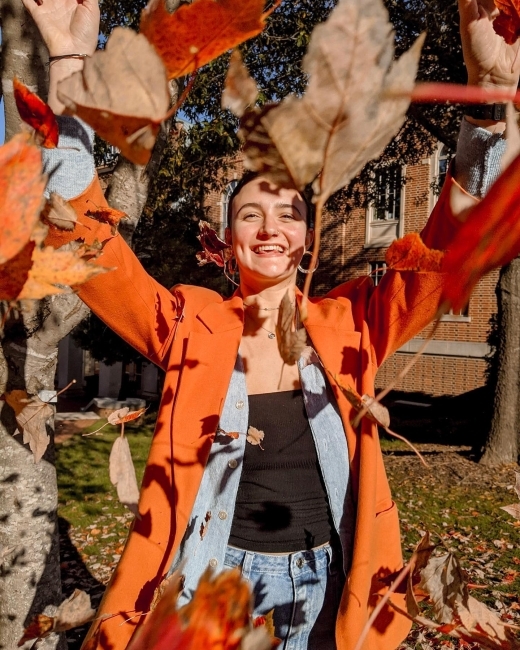 student throws leaves into the air