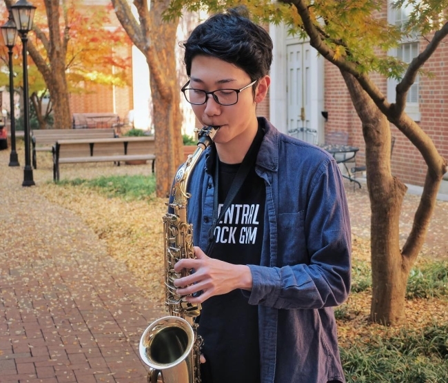 A senior saxophone player playing outdoors