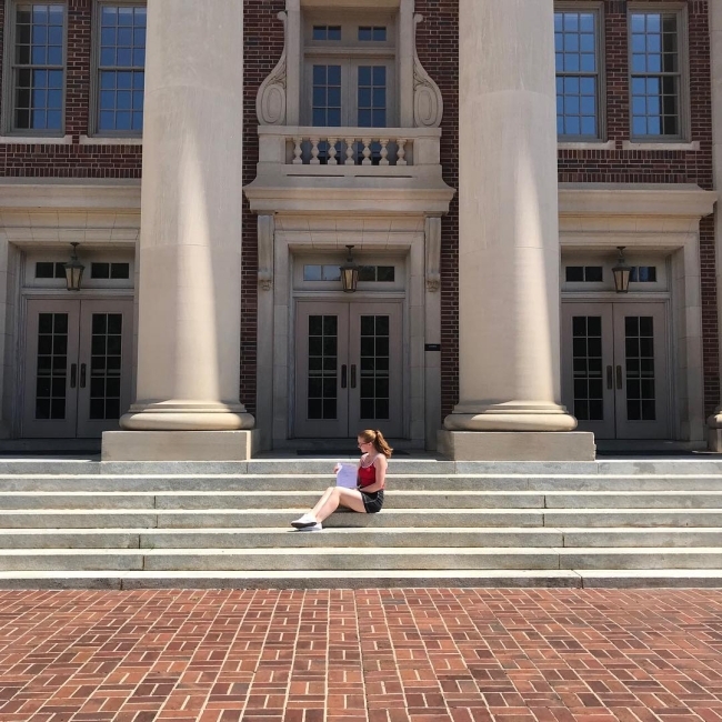 compsci student seated on the steps of college building