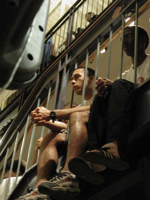 seated Davidson students with legs hanging through rails of second floor Union