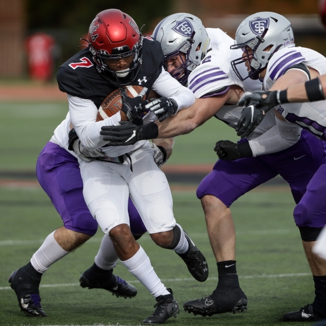 Football Player Holds onto Ball While Getting Tackled