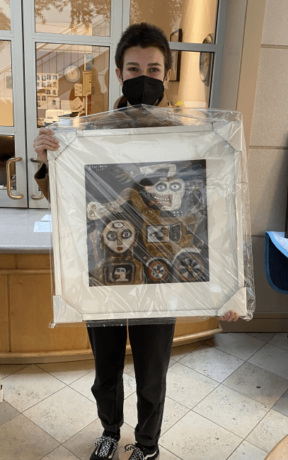 student holds framed artwork