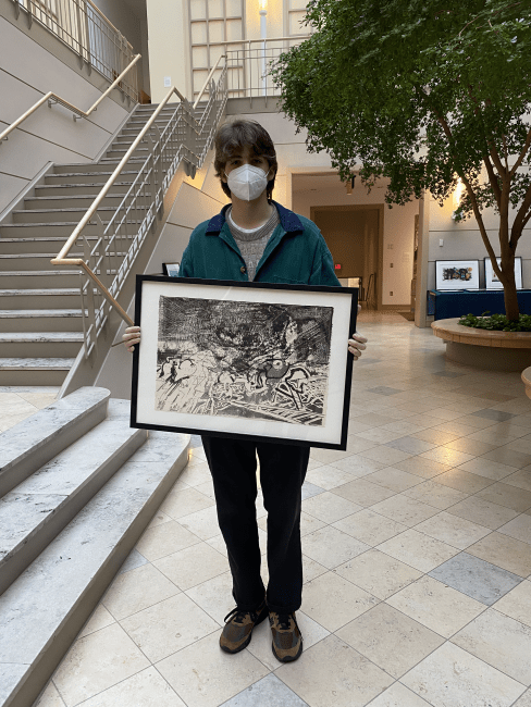 student holds artwork