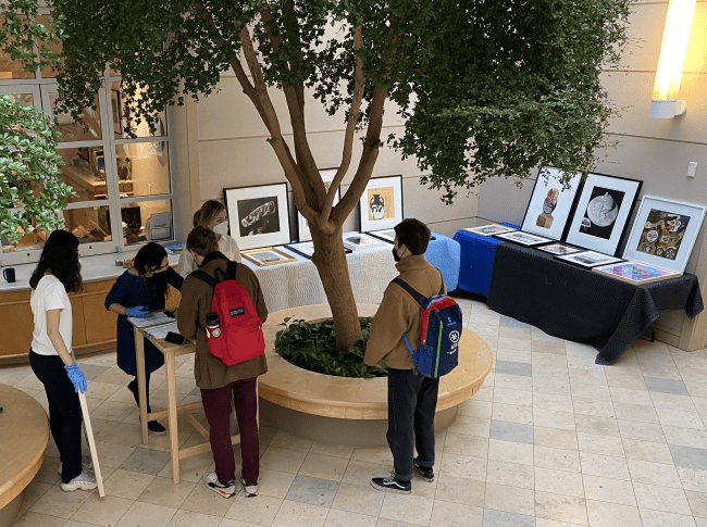 students around tables of artwork displayed