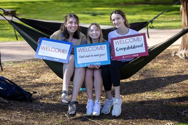 Admission Welcome -- Students Holding Signs on Hammock