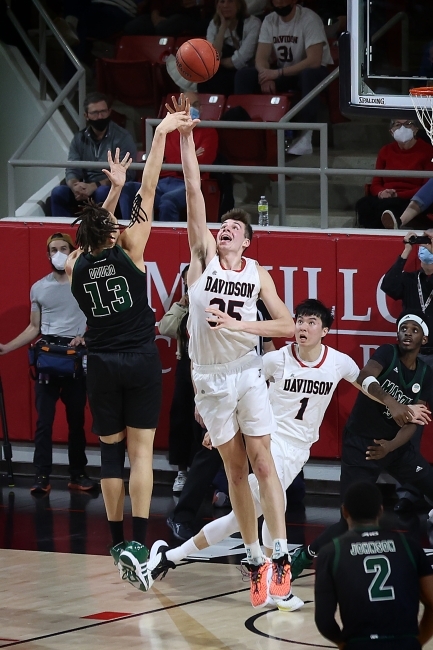 Davidson basketball player jumping for ball near hoop during a game