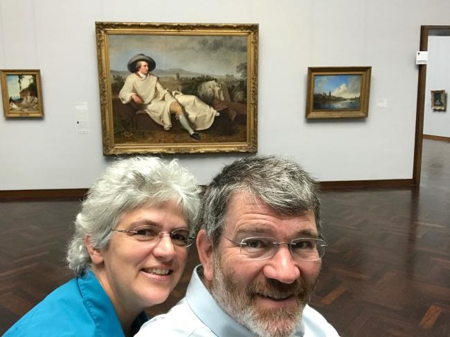 Scott and Cathy Denham smiling in front of famousr German art piece