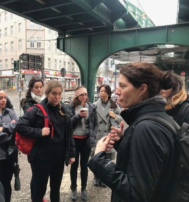 Students in city listening to woman speak