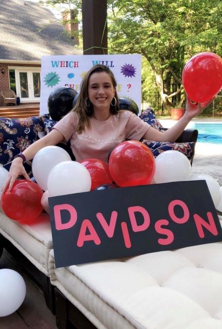 Girl holding balloons and sign that says "Davidson"
