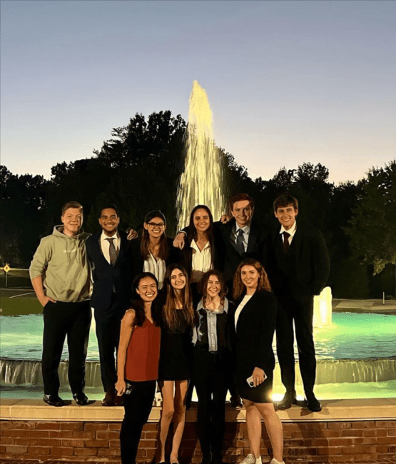 students standing in suits in front of fountain