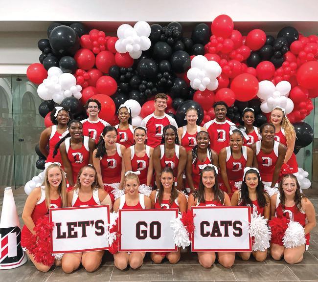 Group photo of cheer team holding signs reading "Let's Go Cats"