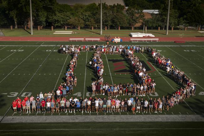 students on football field organized to spell out "D"