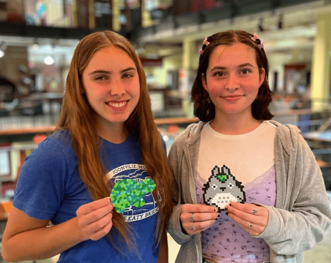 students smiling and holding crafts in their hands