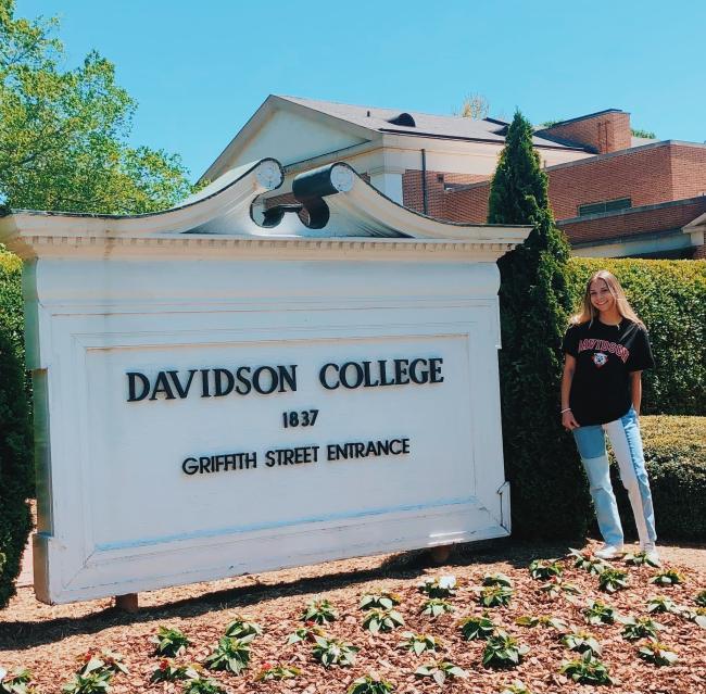 Student standing in front of Davidson College sign