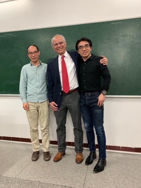 Professor standing with students in front of blackboard