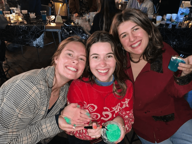 three women smiling and holding potion bottles