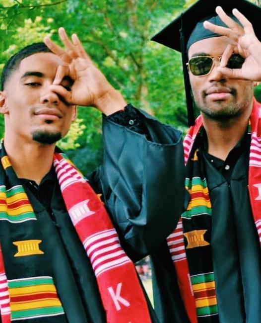 Two fraternity men in graduation robes