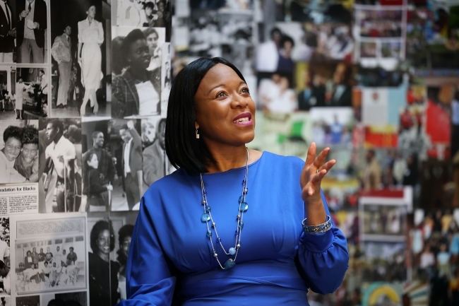 Black woman in front of "BSC Through the Decades" exhibit