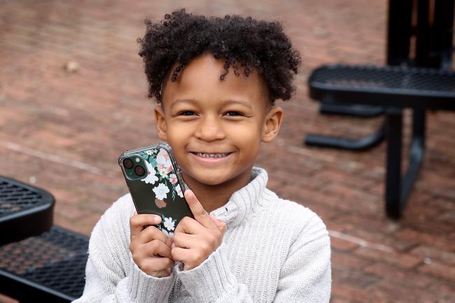 Child smiling and holding a phone