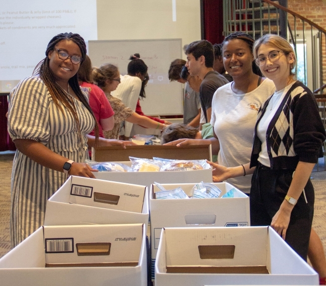 Three women standing together around boxes filled with personal products