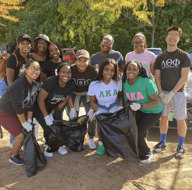 Group of students holding trash bags and smiling