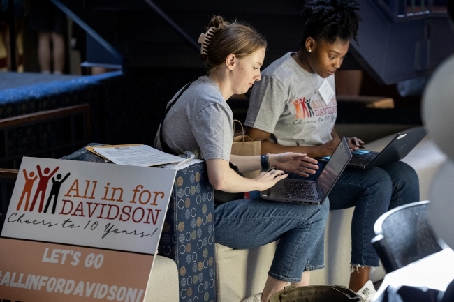 Two women sit around laptops