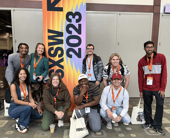 Group of students standing in front of a sign that says "SXSW"