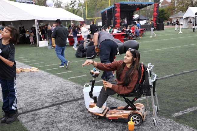 Student in wheelchair throwing a bean bag on football field