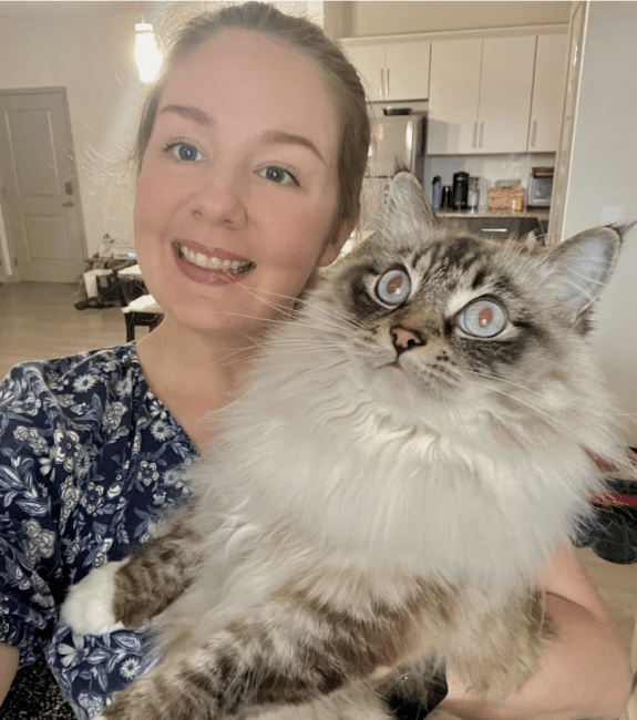 A white woman holding a cat and smiling
