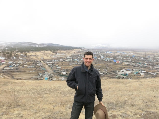 A white male stands in front of a wide landscape and smiles