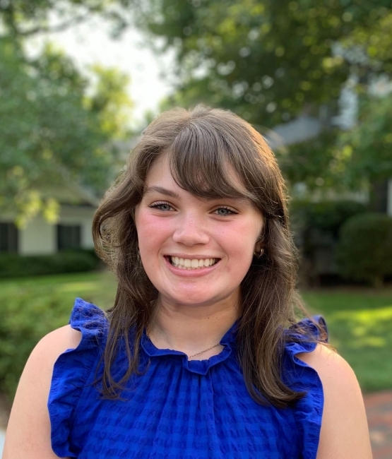 A young white woman smiles and wears a royal blue top